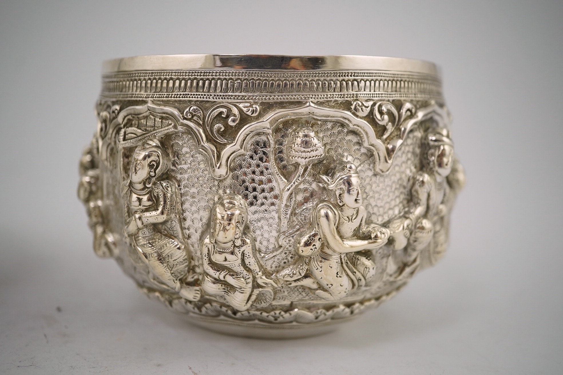 A pair of Burmese white metal bowls, embossed with figures, 12cm diameter, 220 and 224g and a plainer bowl, 110g. Condition – fair